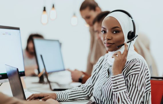 African American Muslim woman with hijab and headset working as customer support in a modern office