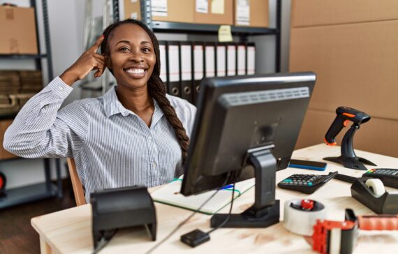 African woman working at small business ecommerce smiling pointing to head with one finger, great idea or thought, good memory